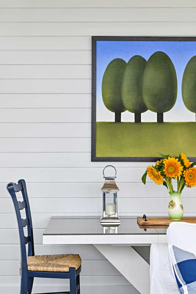 outdoor deck with vibrant painting, fresh flowers and farmhouse style table